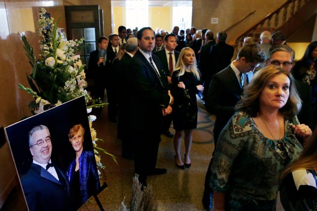 People stand near an image of John and Joyce Sheridan at their funeral in October 2014.